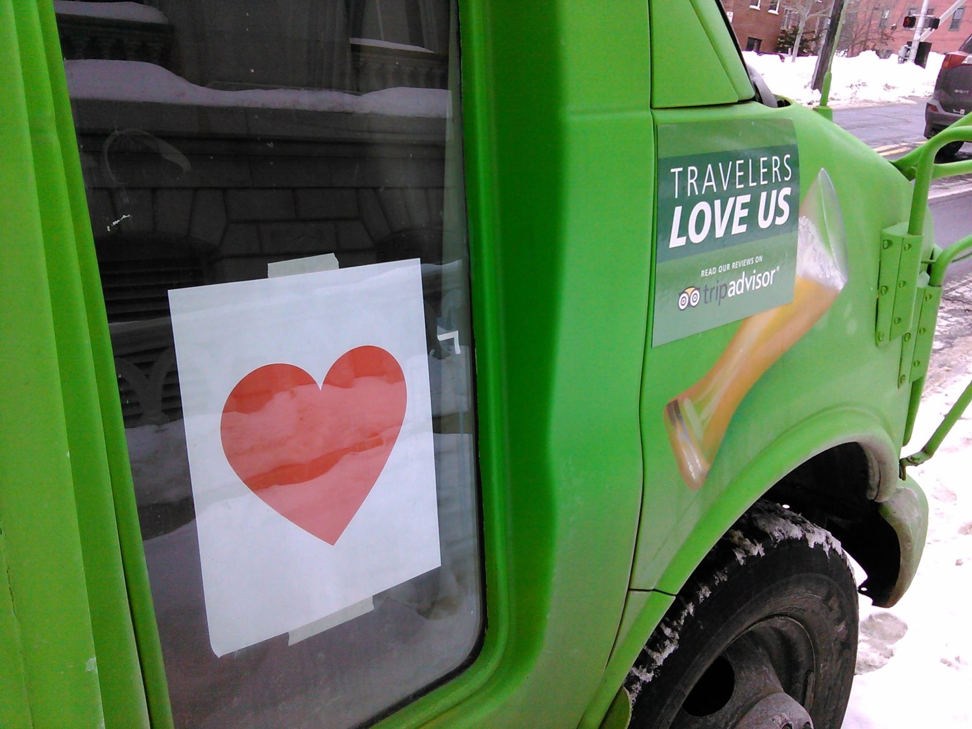 Maine-Brew-Bus-with-Heart-Sign a green truck parked in a parking lot