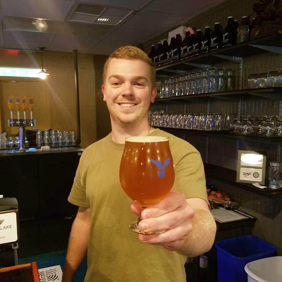 a person holding a glass of beer on a table