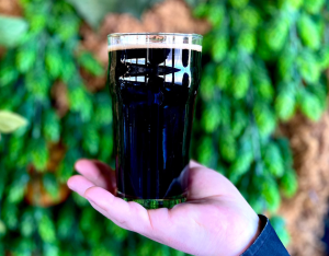 Close up of a Maine Stout in a glass held out by woman's hand