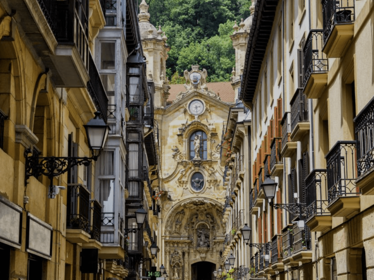 a narrow city street with a clock on the side of a building