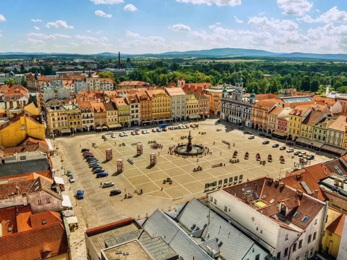 Aerial view of a colorful town square with a fountain and surrounding buildings.