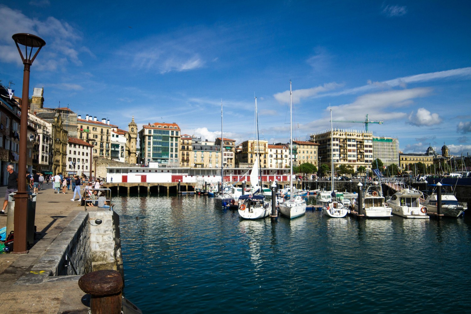 Harbor with docked boats and buildings under a blue sky in a port town.