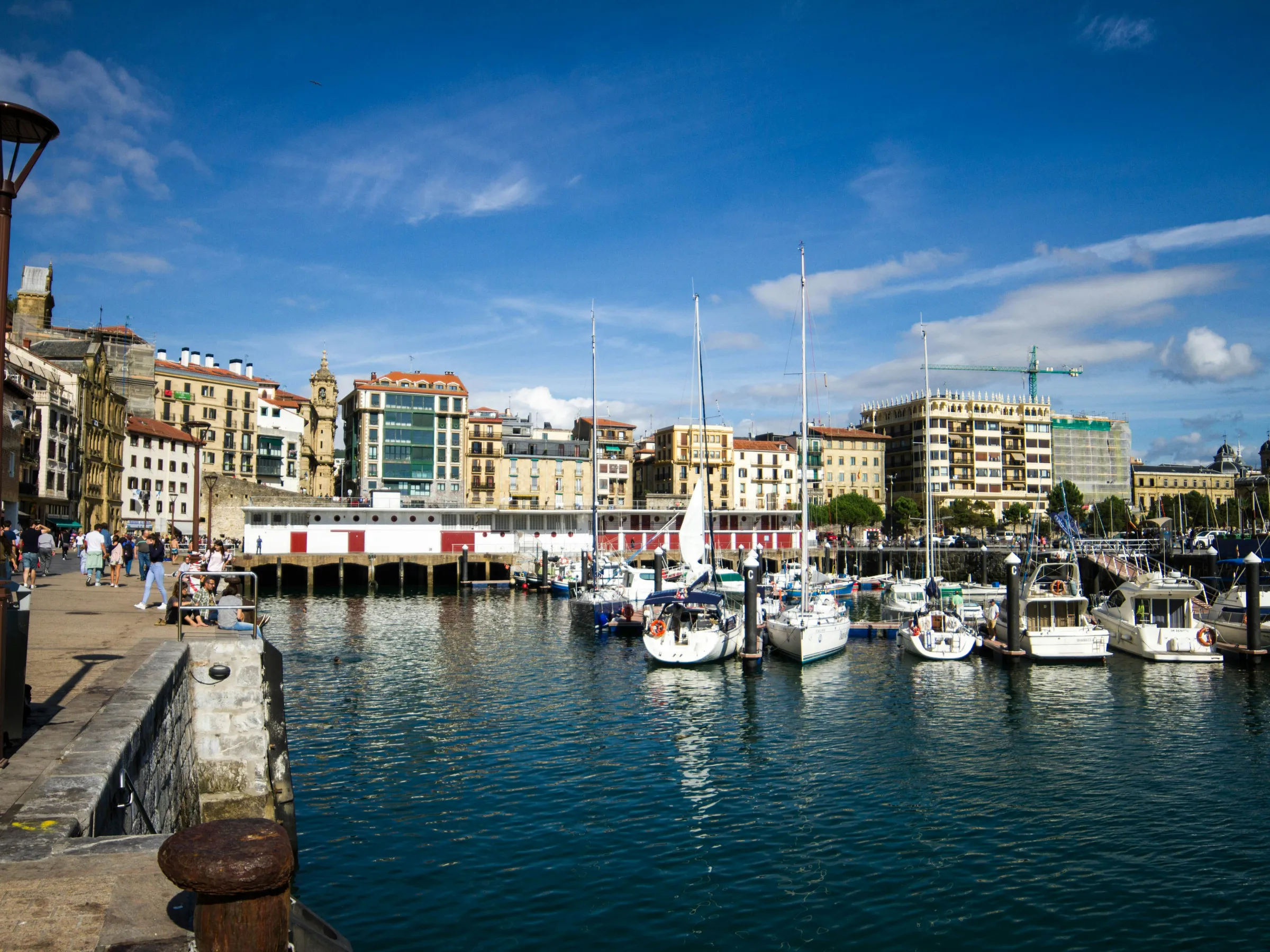 Harbor with docked boats and buildings under a blue sky in a port town.