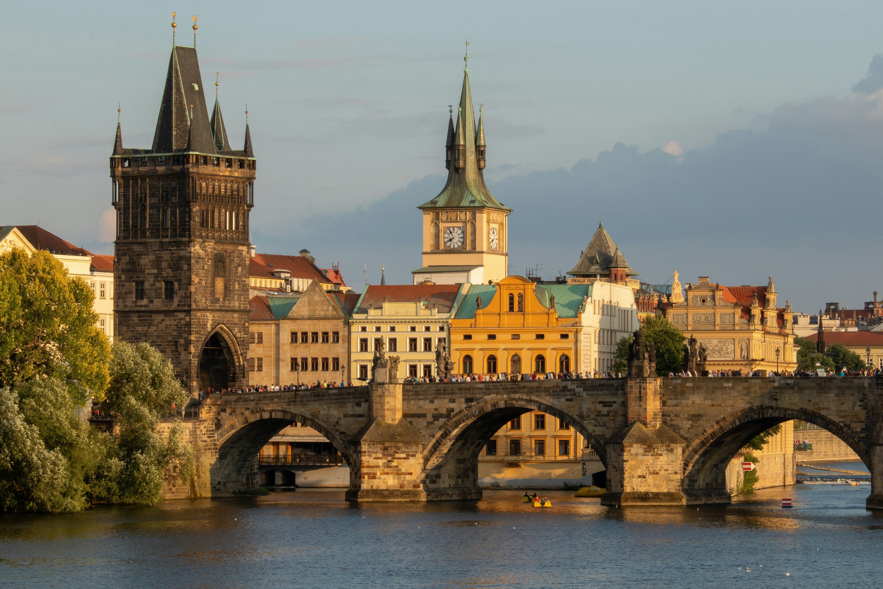 View of Charles Bridge and historic buildings in Prague during sunset.