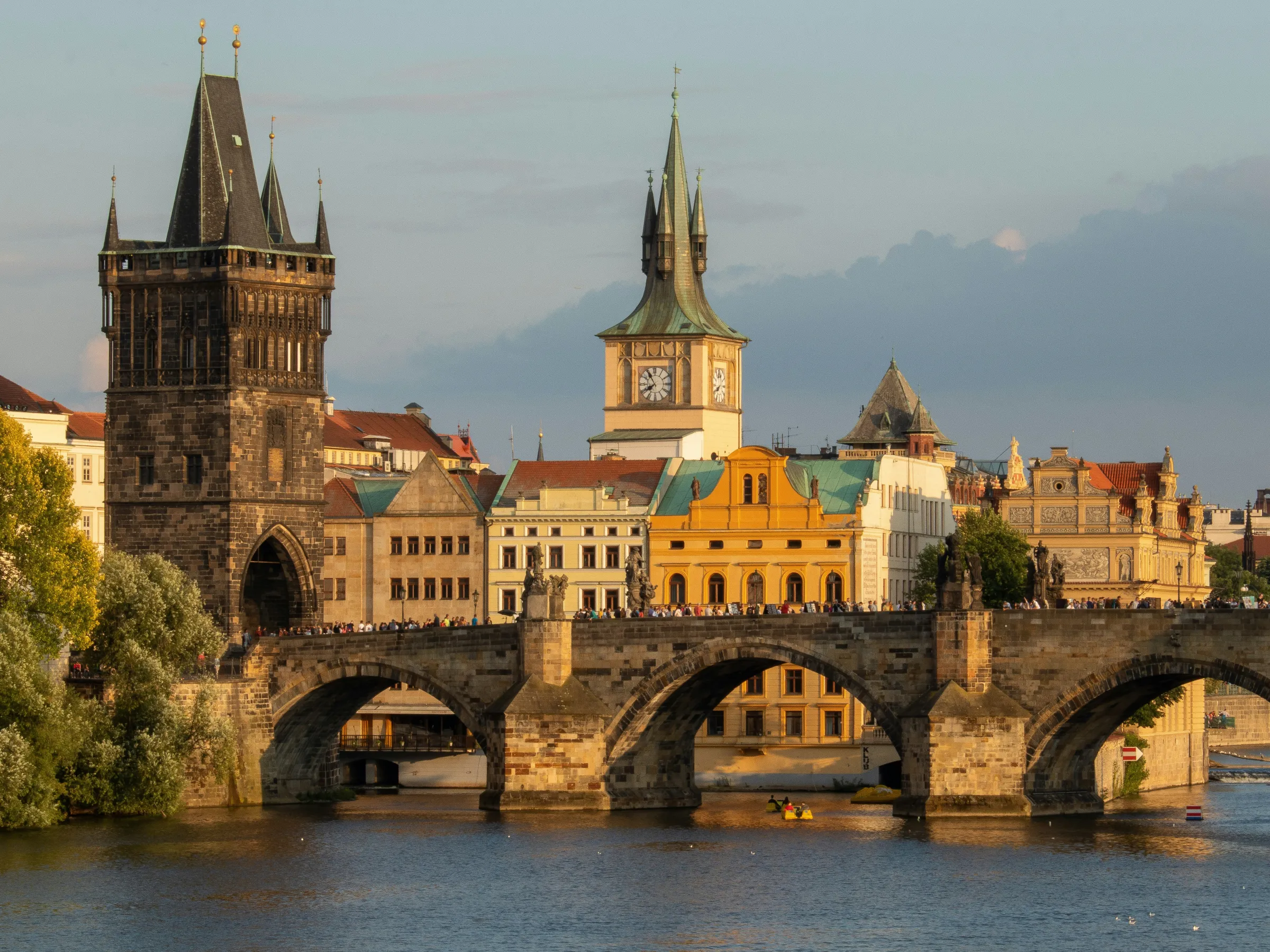 View of Charles Bridge and historic buildings in Prague during sunset.