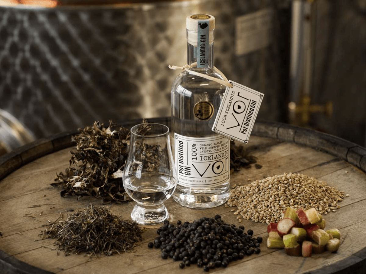 Bottle of Icelandic gin on barrel with various herbs and grains.