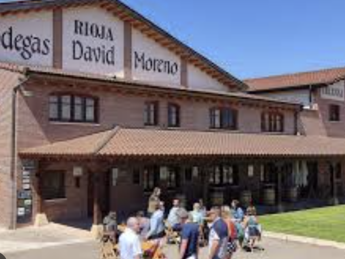 People outside Bodegas David Moreno, a brick winery with signs on the building.