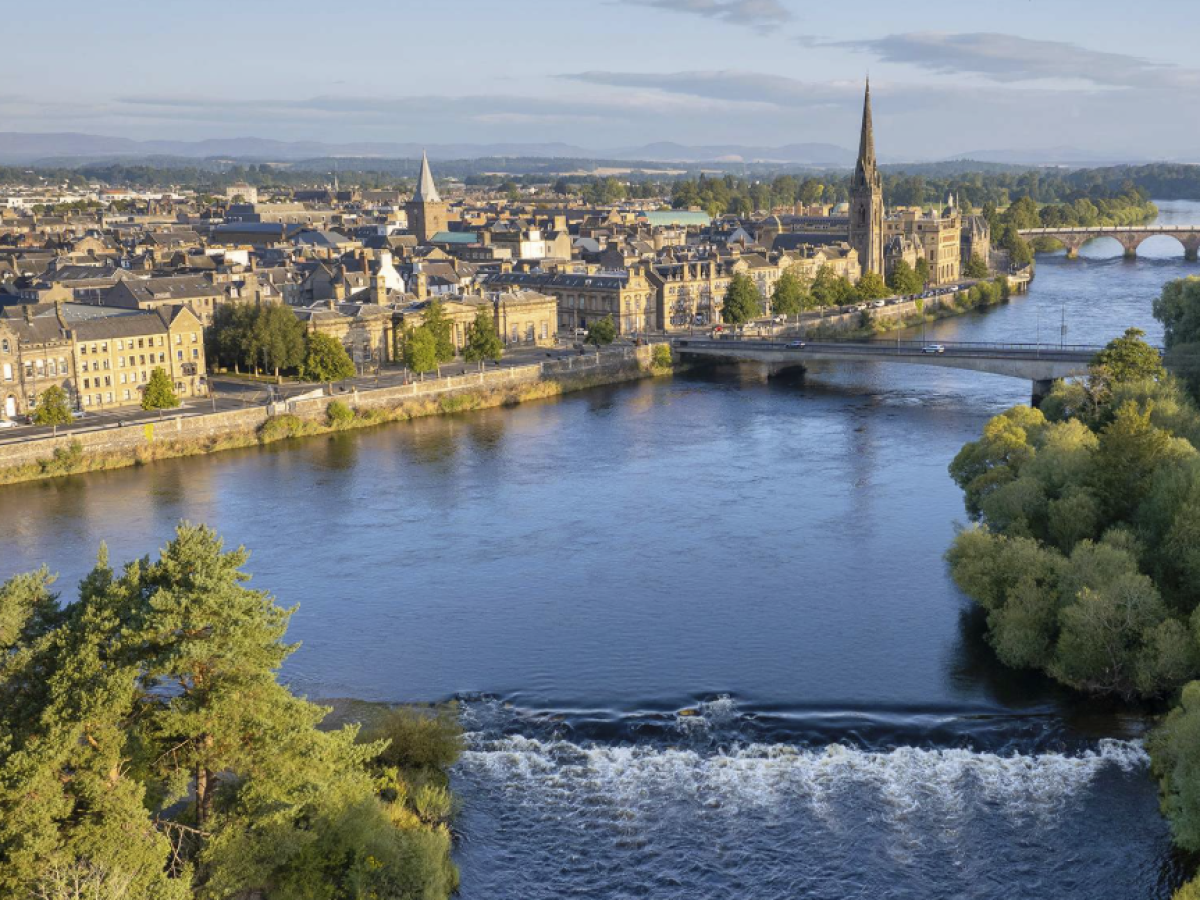 Aerial view of Perth cityscape with river, bridge, and cathedral.