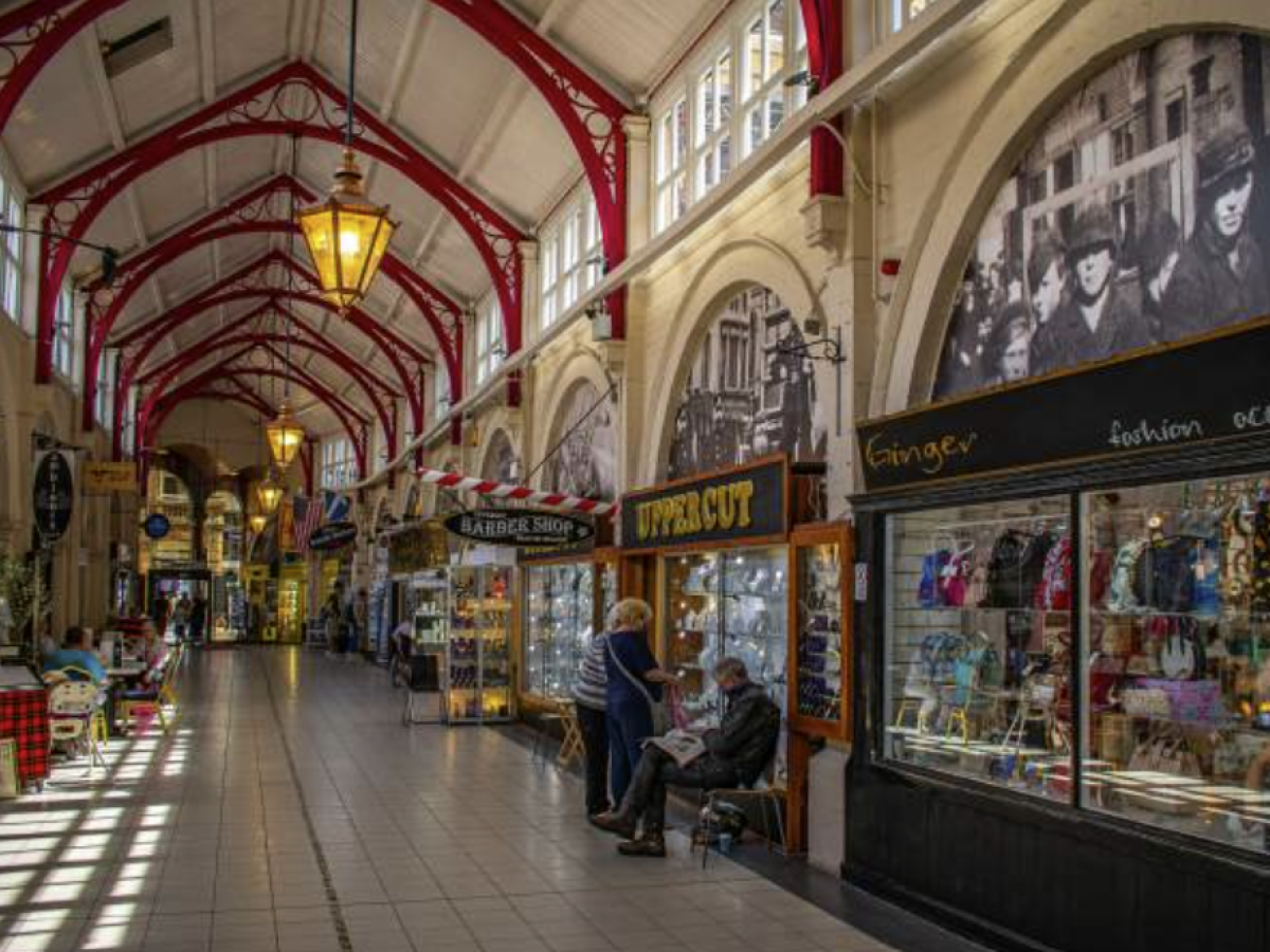Indoor market with arched ceiling, shops, and people walking.