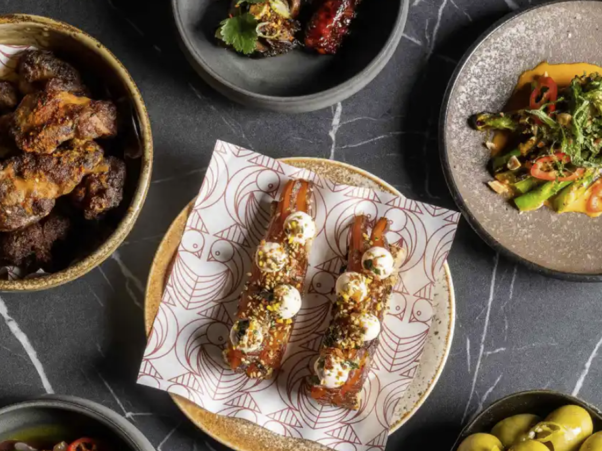 Assorted dishes with grilled meats and vegetables on a dark marbled table.