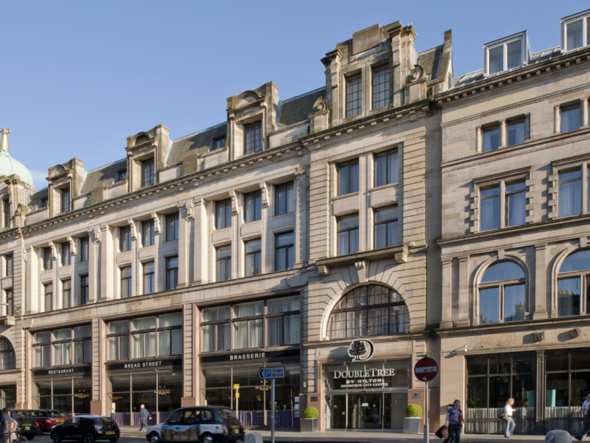 Historic building with a DoubleTree hotel and dome on the left, under a clear blue sky.