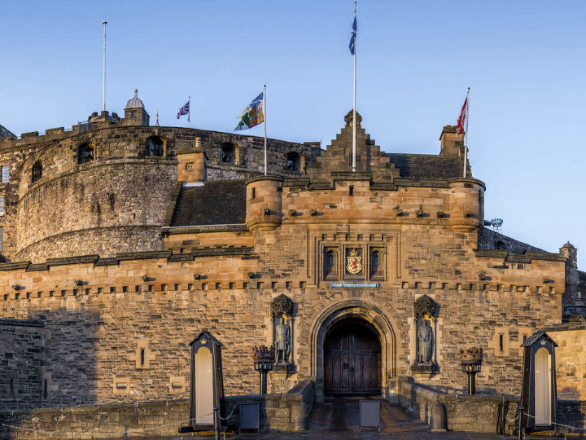 Front view of a stone castle with flags and an arched entrance.