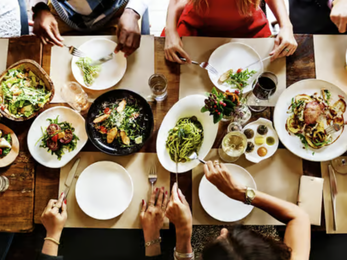 Top view of people dining with various dishes on a wooden table.