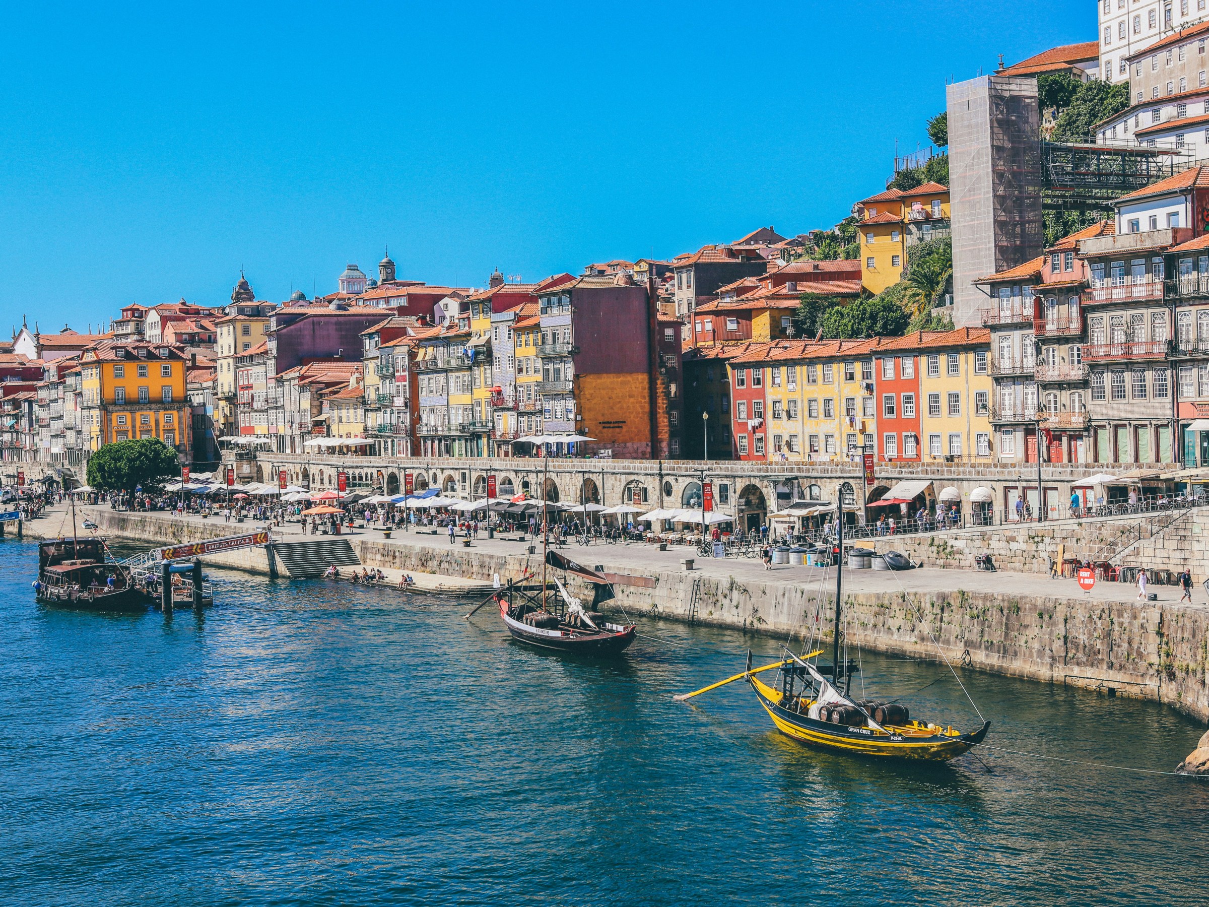Colorful buildings lining a riverside promenade with boats in the water.