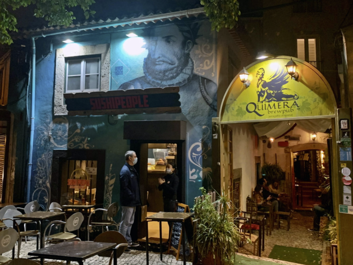 Outdoor dining area with two adjacent restaurants, one with a mural, at night.
