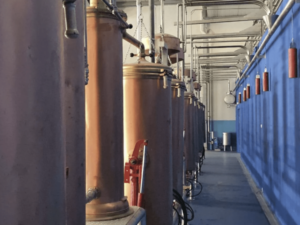 Indoor industrial setting with large metal cylinders and blue-painted walls.