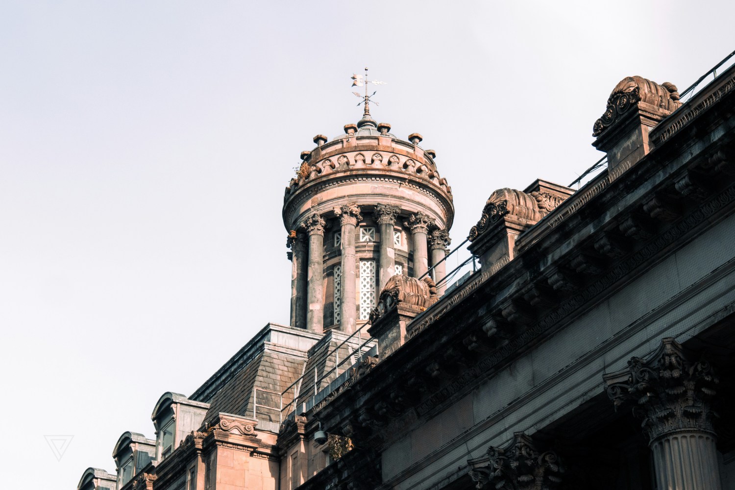 Ornate architectural building with a cylindrical tower and decorative columns under a clear sky.