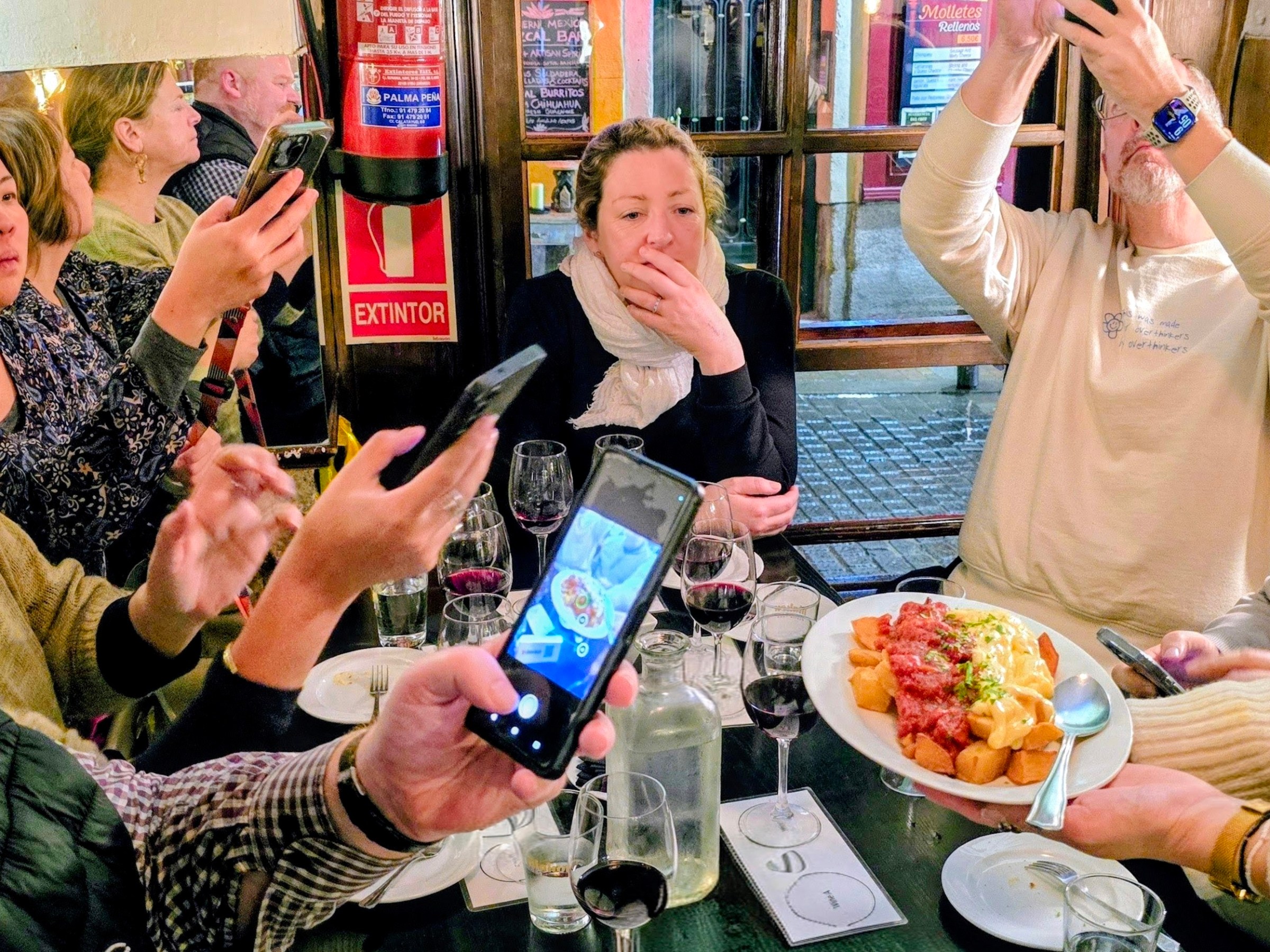 People at a restaurant table taking photos of food with their smartphones.