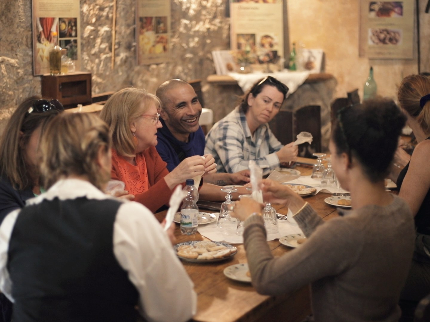 People gathered around a table in a rustic room, sharing a meal and talking.