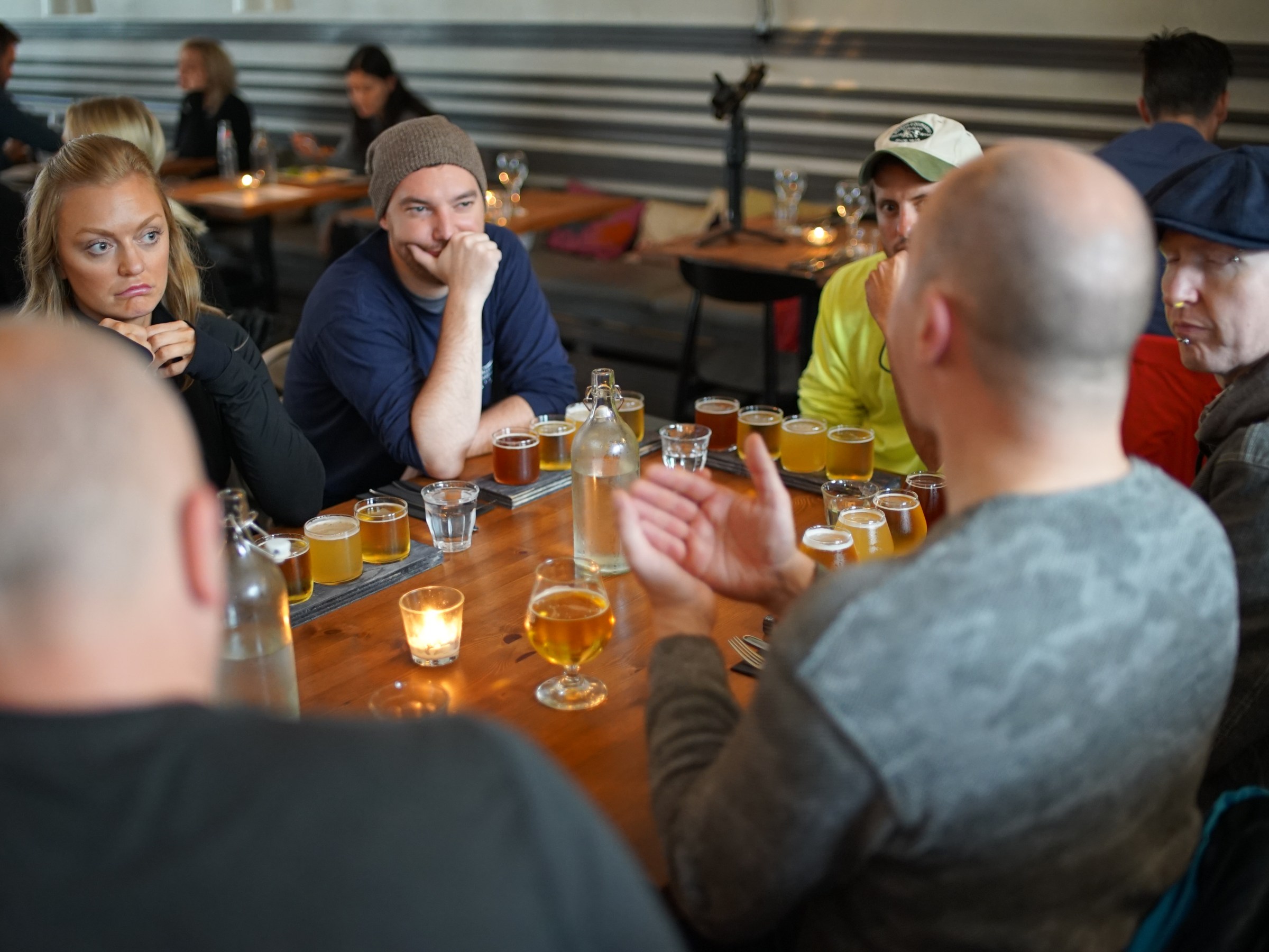 Group of people sitting at a table with drinks, talking and listening.