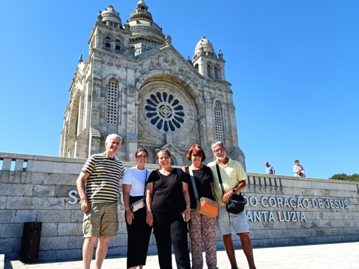 Five people smiling in front of a large cathedral with clear blue skies.