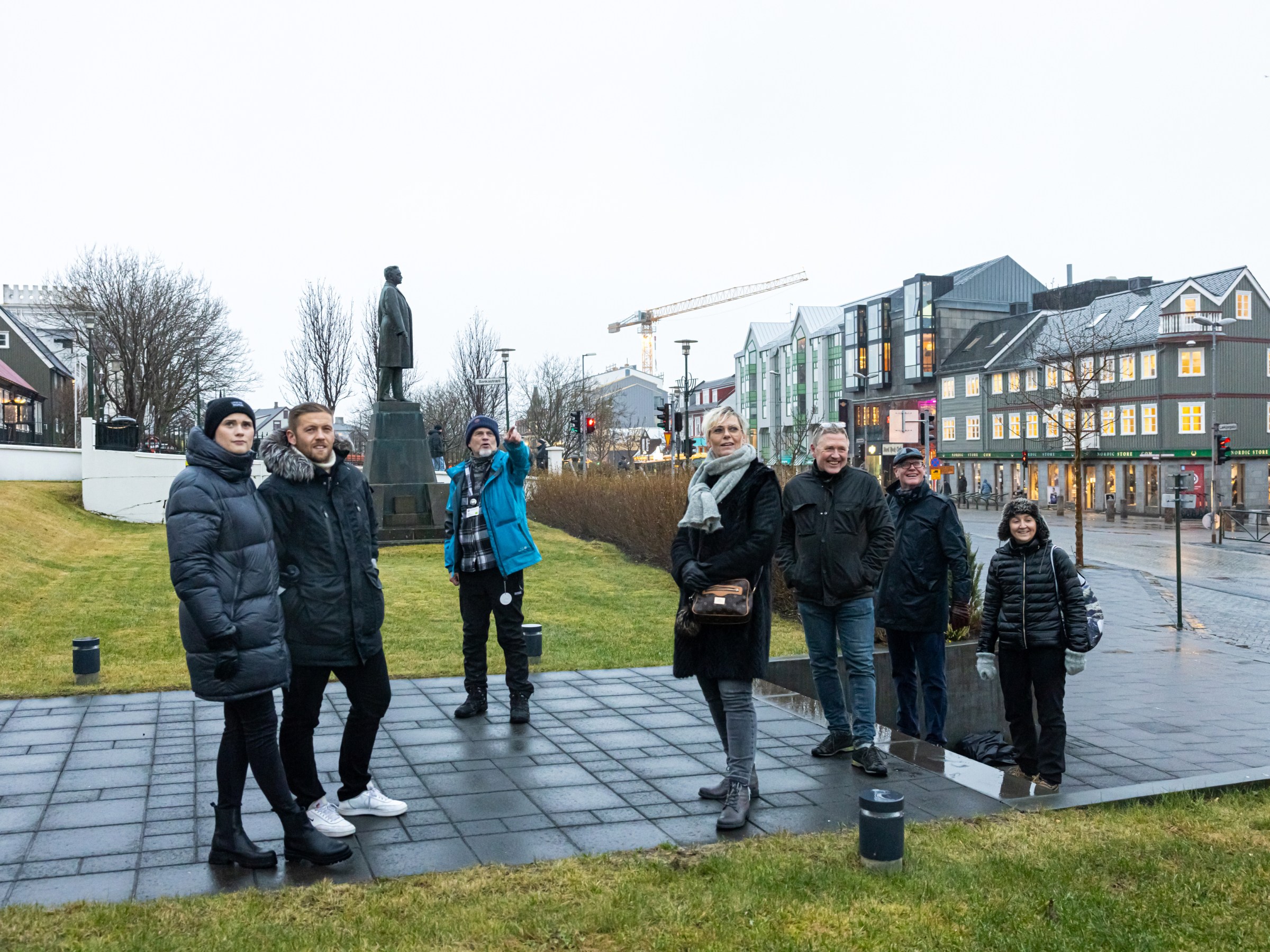 Group of people posing in front of a statue in a town square with colorful buildings.