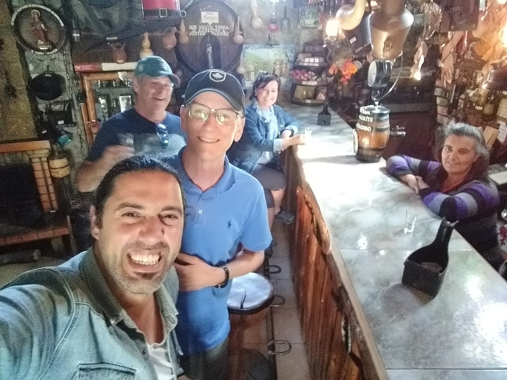 Five people smiling in a cozy, rustic bar with memorabilia on the walls.