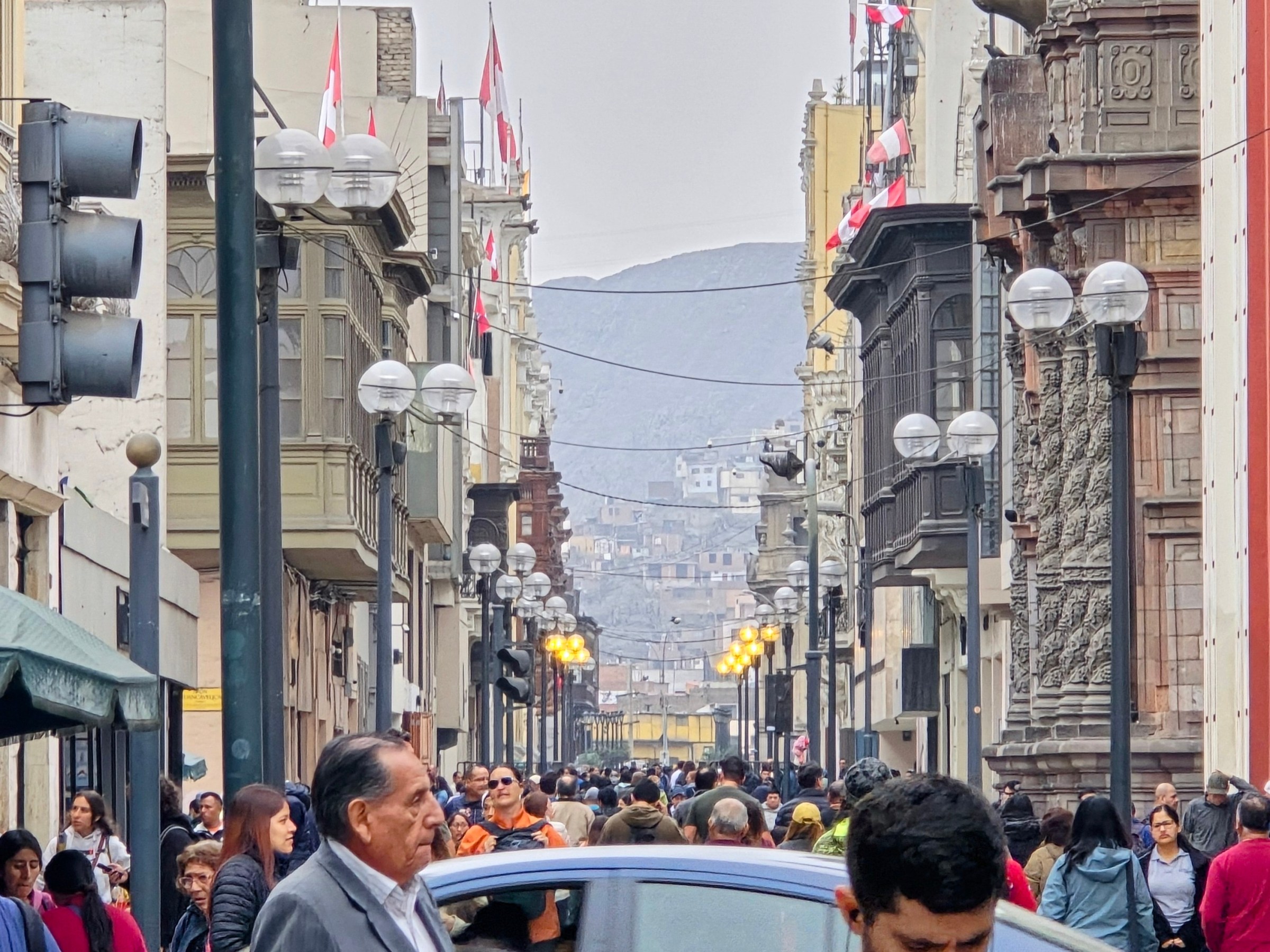 Crowded city street with historic buildings and flags.