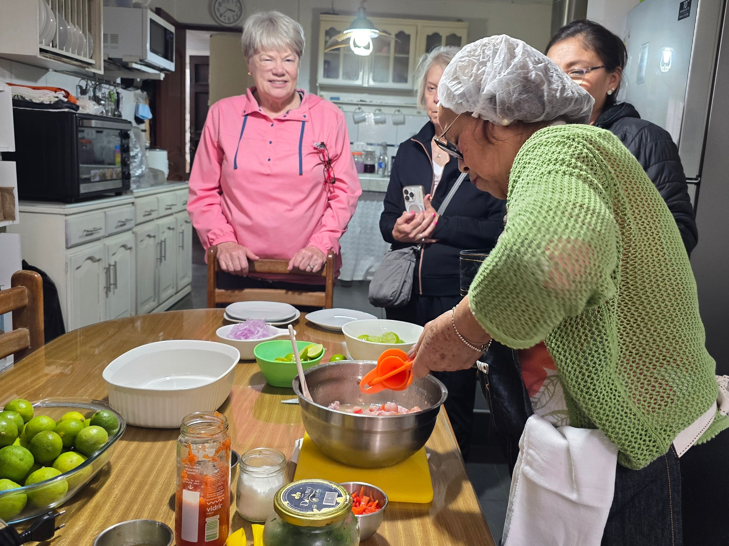 Four people in a kitchen, one preparing food in a bowl, others watching.