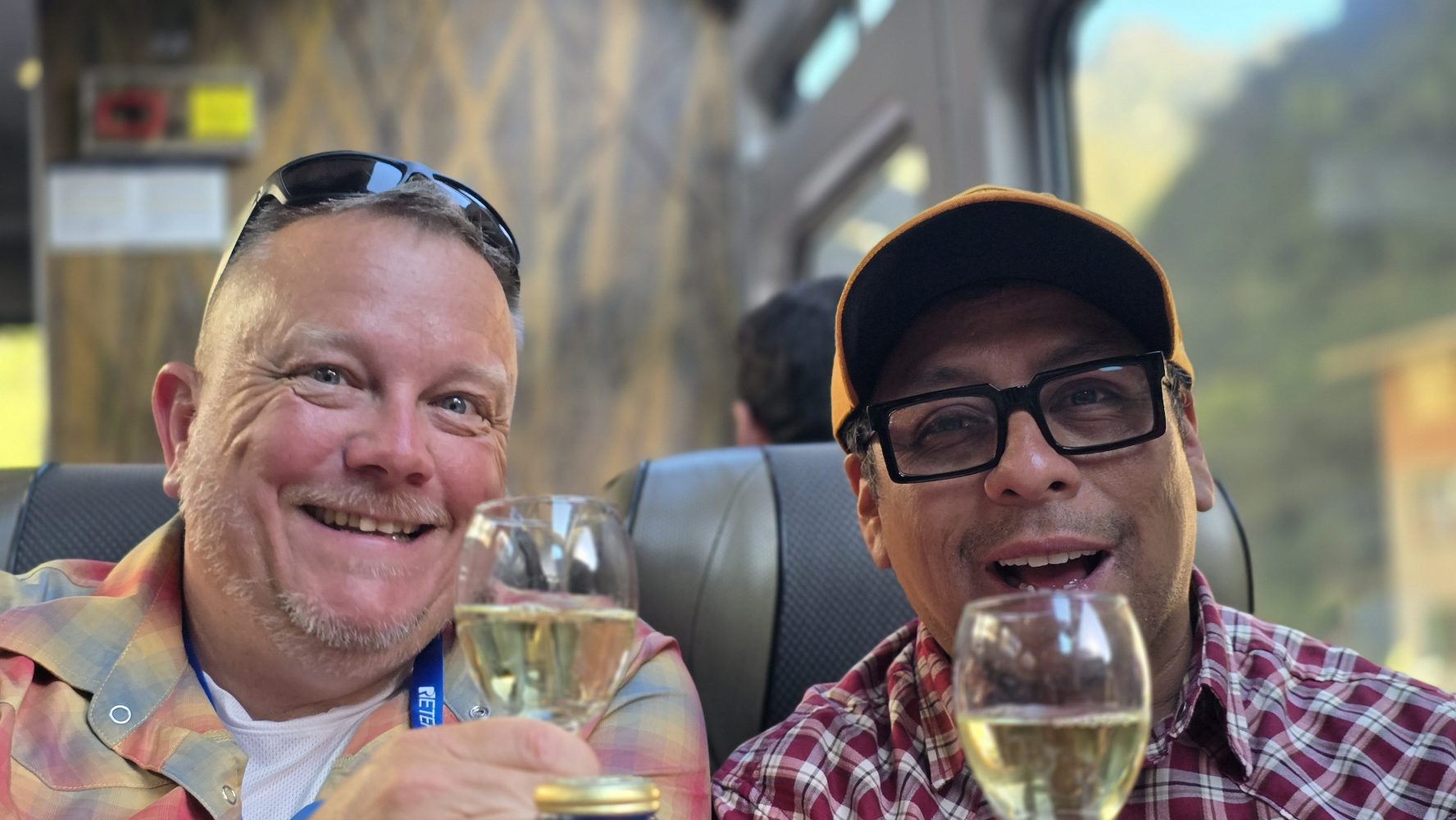 Two people upside down, toasting with drinks inside a train.